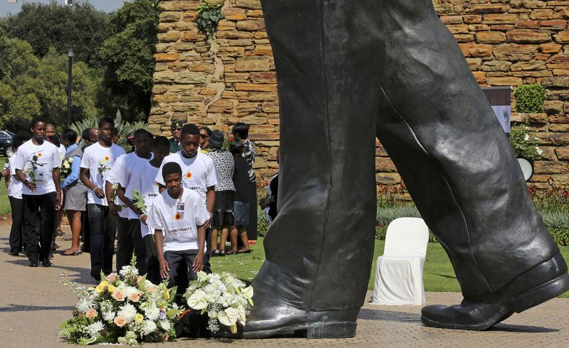 © Reuters. Estudantes depositam flores em estátua de Mandela em Pretória