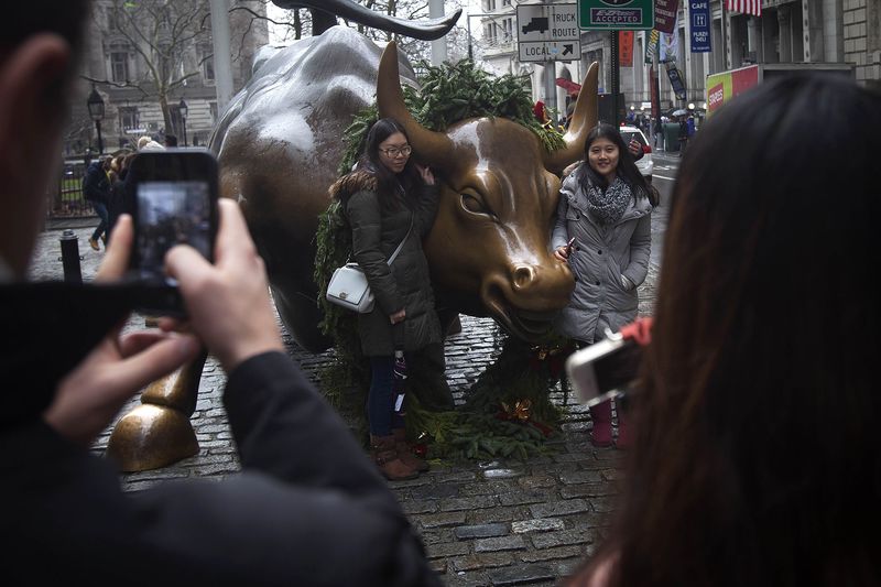 © Reuters. Tourists pose for photos with the Wall Street bull statue in the Manhattan Borough of New York