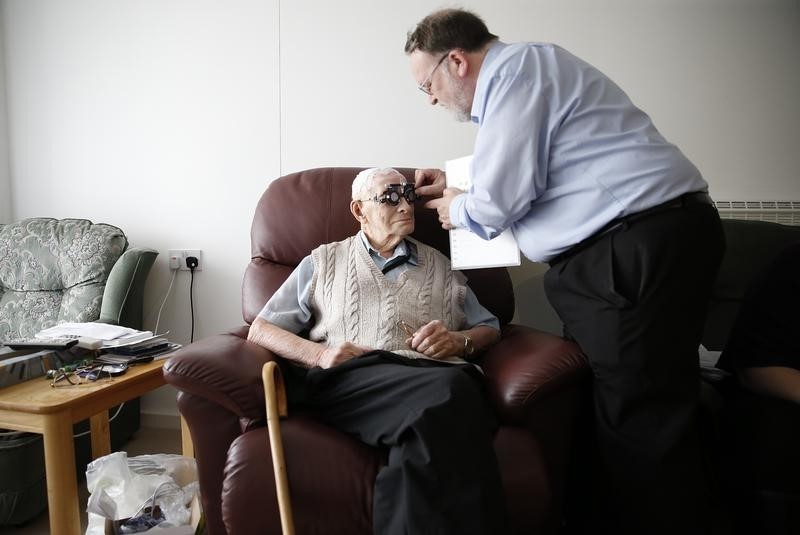 © Reuters. Resident Ernie Mayes, 89, has his eyes checked by Optometrist in his flat at the Colbrooke House care facility run by a private company working on behalf of the local government and housing association in southeast London