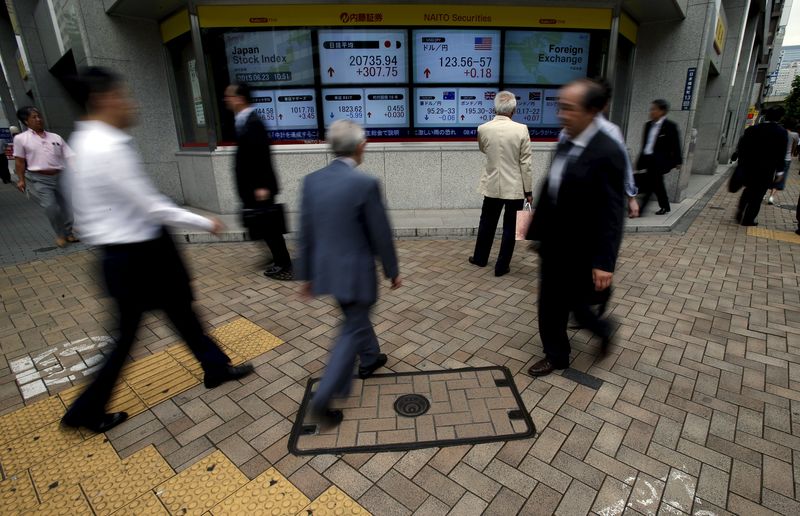 © Reuters. Pedestrians walk past electronic boards showing Japan's Nikkei average and the exchange rates between the Japanese yen against the U.S. dollar outside a brokerage in Tokyo
