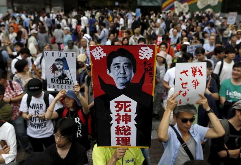 © Reuters. Protesters holding placards participate in a rally against Japanese Prime Minister Shinzo Abe's administration in Tokyo