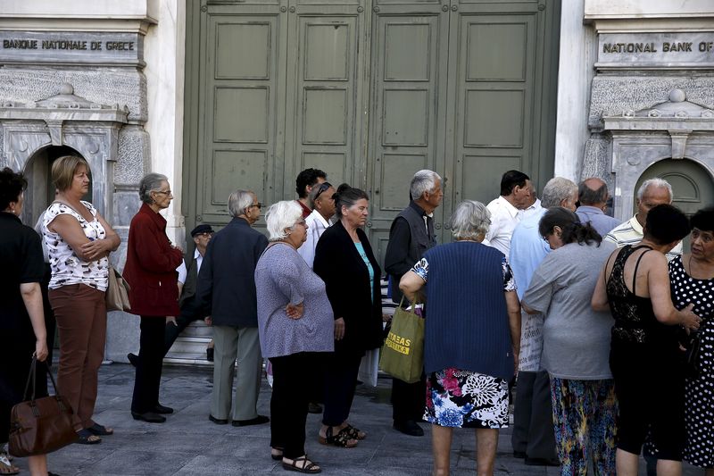 © Reuters. People, most of them pensioners, line up outside a closed National Bank branch at the bank's headquarters in Athens