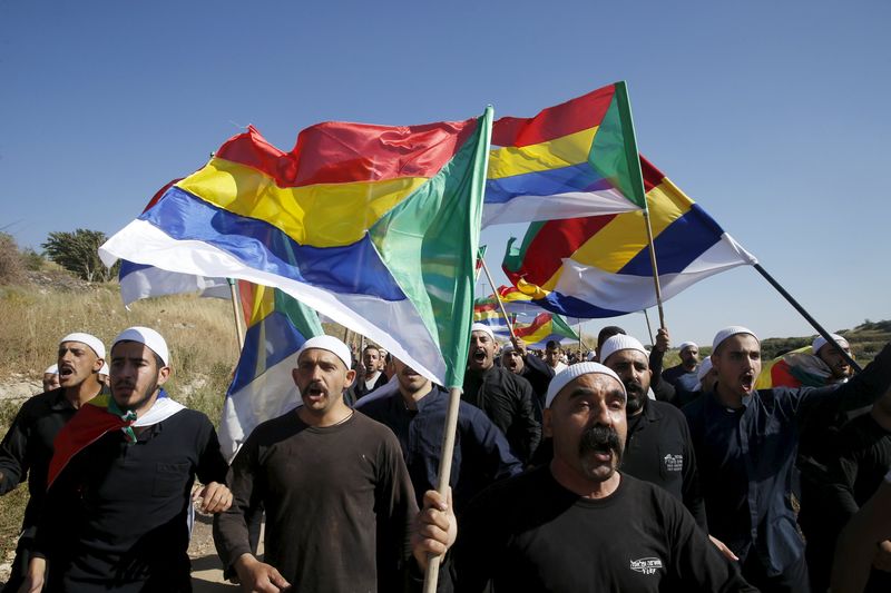 © Reuters. Members of the Druze community carry flags at they walk towards the border fence in Israeli-occupied Golan Heights