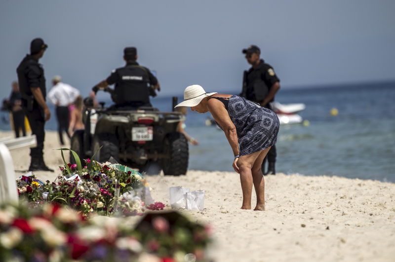 © Reuters. A tourist reads messages left at a makeshift memorial at the beach near the Imperial Marhaba resort, which was attacked by a gunman in Sousse