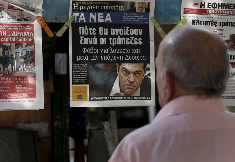 © Reuters. A man reads the front pages of various newspaper hanging at a kiosk in Athens