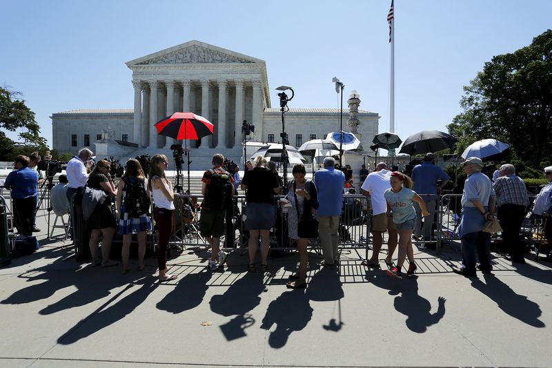 © Reuters. Tourists watch as television news crews report on decisions handed down on the last day of the term at the U.S. Supreme Court building in Washington