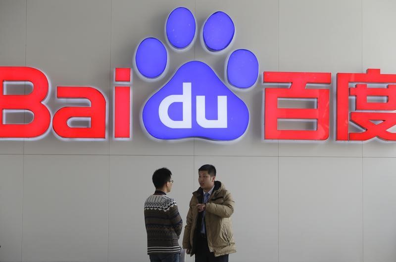 © Reuters. People talk in front of a Baidu's company logo at Baidu's headquarters in Beijing