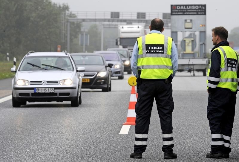 © Reuters. Danish customs officers watch traffic at a checkpoint on the German-Danish border crossing in Froslev