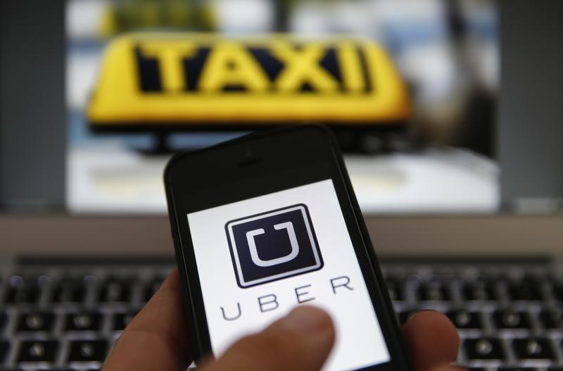 © Reuters. An illustration picture shows the logo of car-sharing service app Uber on a smartphone next to the picture of an official German taxi sign