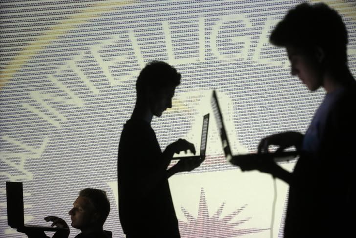 © Reuters. People pose with laptops in front of projection of  binary code and CIA emblem in this picture illustration taken in Zenica