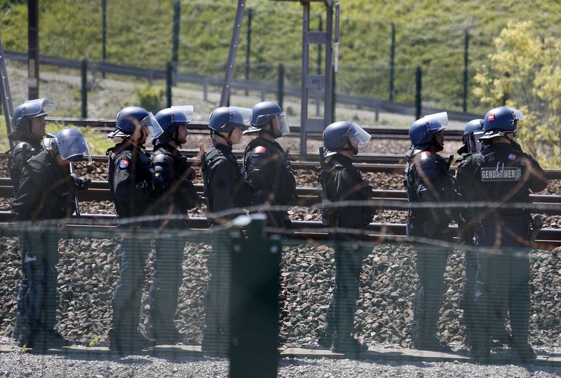 © Reuters. French gendarmes stand near the tracks after workers operating on the MyFerryLink car and passenger ferry boats set tires into fire at the entrance of the Eurotunnel Channel Tunnel linking Britain and France in Coquelles near Calais