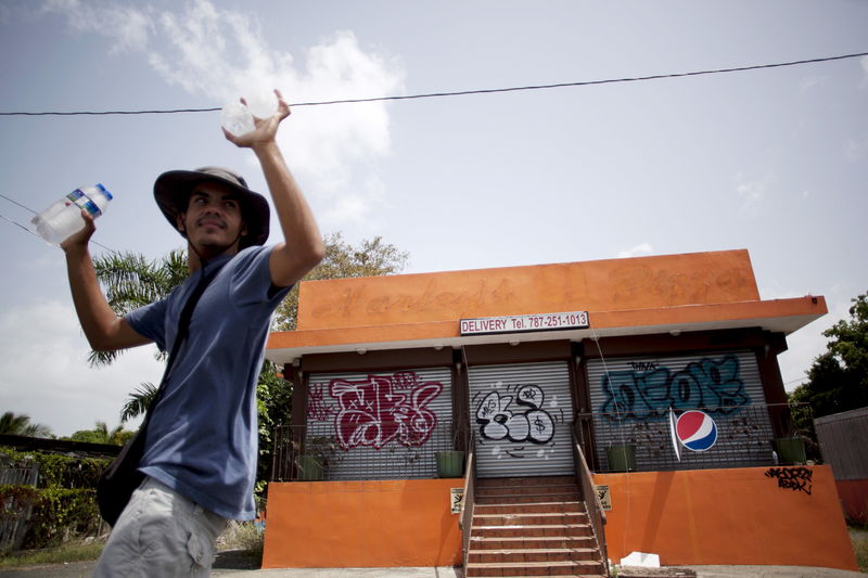 © Reuters. A young man offers water for sale outside a closed pizzeria in Toa Alta