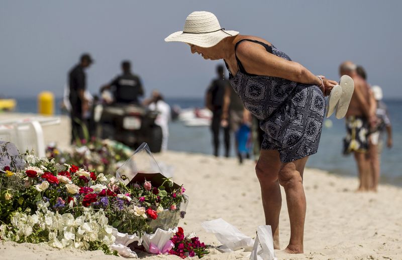 © Reuters. Turista lê mensagens deixadas num memorial na praia na Tunísia