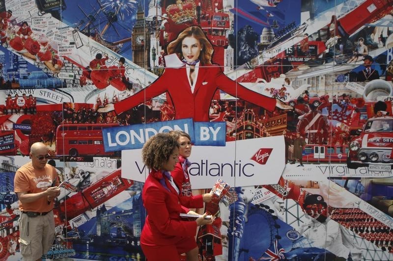 © Reuters. Crew members of Virgin Atlantic Airways handout flags while walking past large placard in Union Square in New York