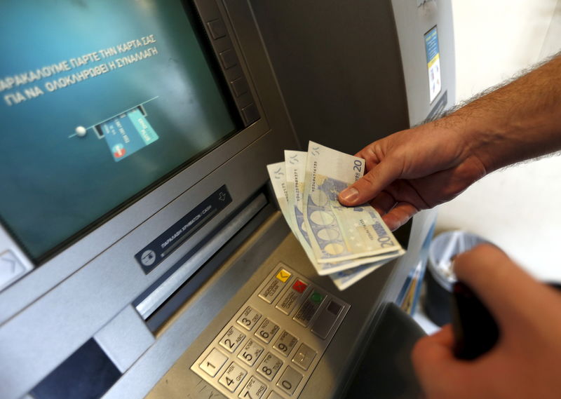 © Reuters. A man withdraws sixty Euros, the maximum amount allowed after the imposed capital controls in Greek banks, at a National Bank of Greece ATM in Piraeus