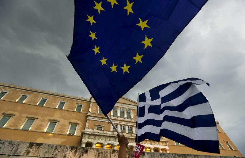 © Reuters. La bandiera greca e sventola di fianco alla bandiera europea durante una manifestazione ad Atene 