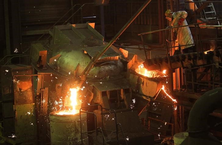 © Reuters. A worker at Belgian company Picanol demonstrates how iron is melted in a foundry at the factory's plant in Ypres