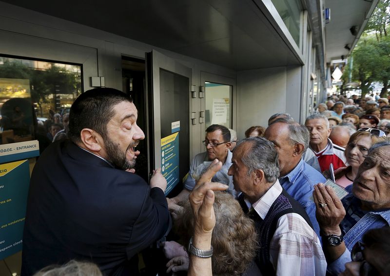 © Reuters. Gerente de banco tenta explicar situação a centenas de pensionistas em fila do lado de fora do Banco Nacional, em Atenas