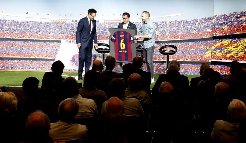 © Reuters. Barcelona's Xavi Hernandez shows Barcelona jersey signed by the whole team between President Josep Maria Bartomeu and his teammate Andres Iniesta during Xavi's farewell event at Auditori 1899 in Nou Camp stadium in Barcelona