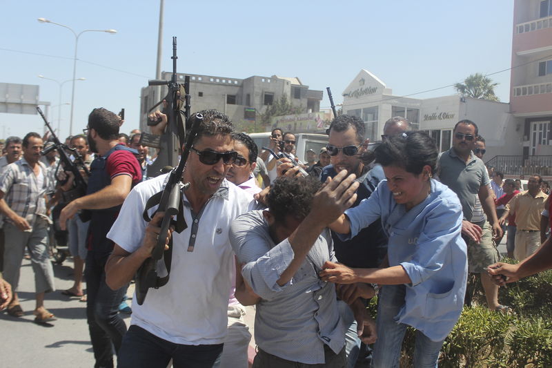 © Reuters. Police officers control the crowd while surrounding a man suspected to be involved in opening fire on a beachside hotel in Sousse