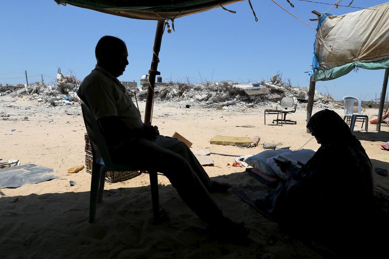 © Reuters. Palestinian woman reads the Koran as she sits in her makeshift shelter near the remains of her house, that witnesses said was destroyed by Israeli shelling during a 50-day war last summer, in Khan Younis in the southern Gaza Strip