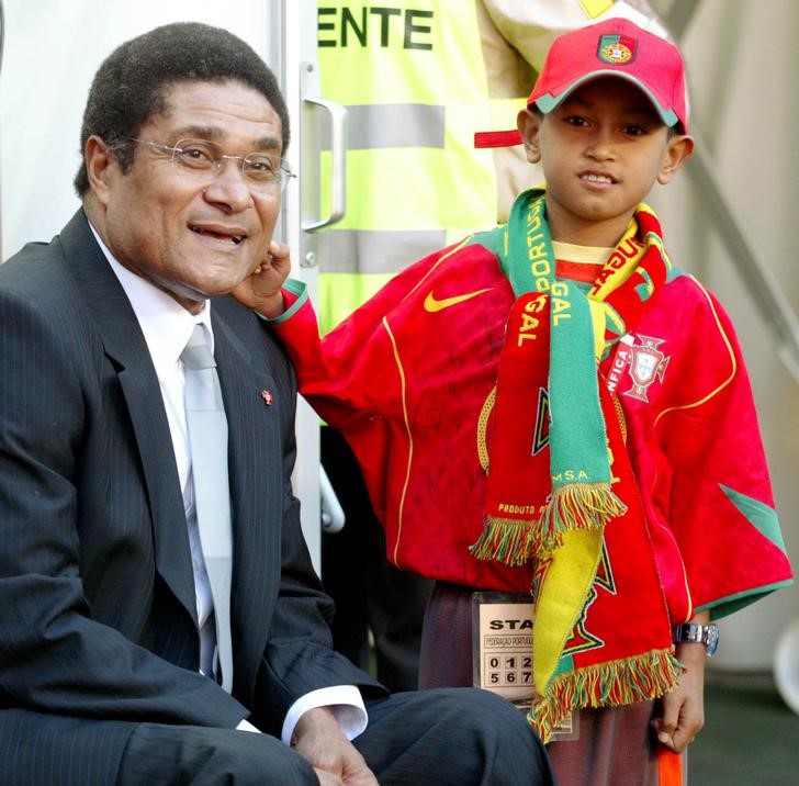 © Reuters. Então com 8 anos, Martunis posa para foto ao lado do ídolo do futebol português Eusébio em Lisboa