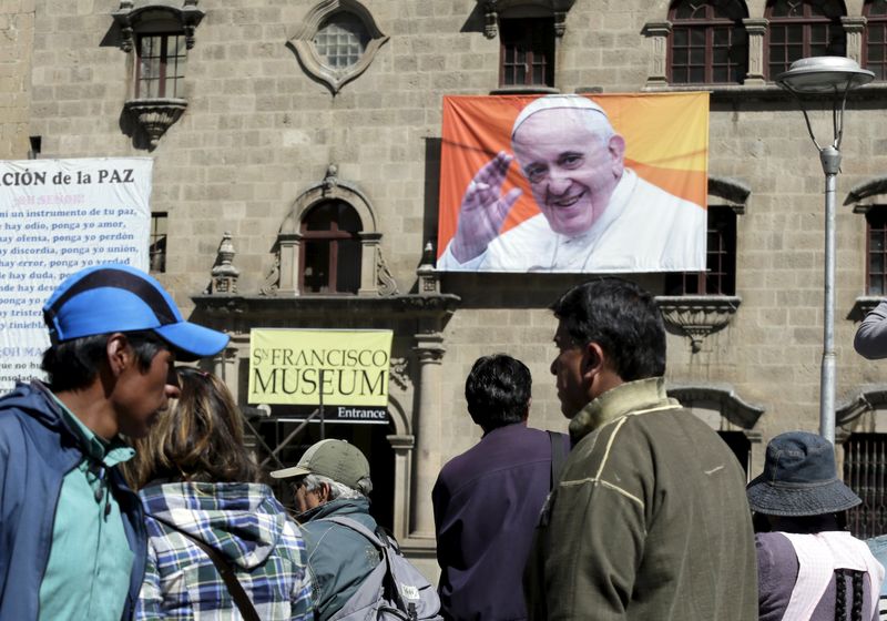 © Reuters. Pedestrians walk at San Francisco square where an image of Pope Francis is displayed in La Paz