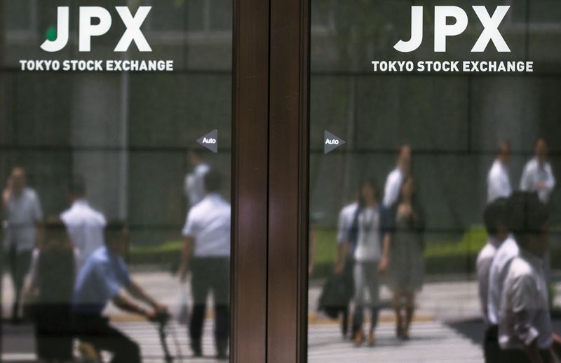 © Reuters. People are reflected in doors of TSE building in Tokyo 