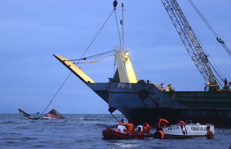 © Reuters. Membros da Guarda Costeira das Filipinas tentam recuperar destroços da balsa naufragada