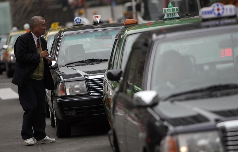 © Reuters. A taxi driver takes a break as he queues outside a train station in Tokyo