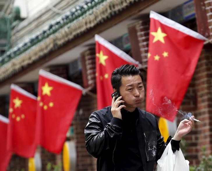 © Reuters. Homem em frente bandeira nacional da China, em Pequim