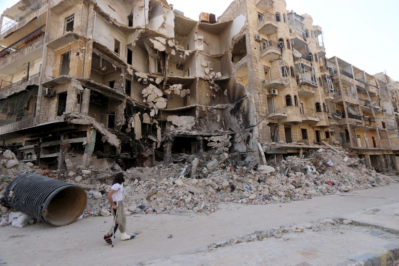 © Reuters. Homem andando por prédios danificados em Aleppo