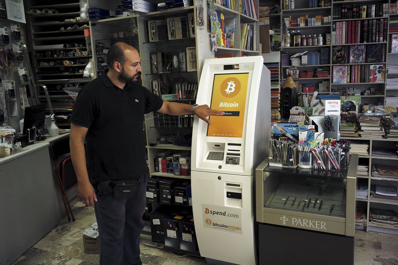 © Reuters. Homem demonstra uso de caixa eletrônico de Bitcoin em livraria em Atenas