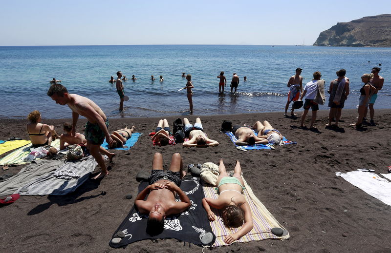 © Reuters. Tourists sunbathe on the Red Beach on the Greek island of Santorini, Greece