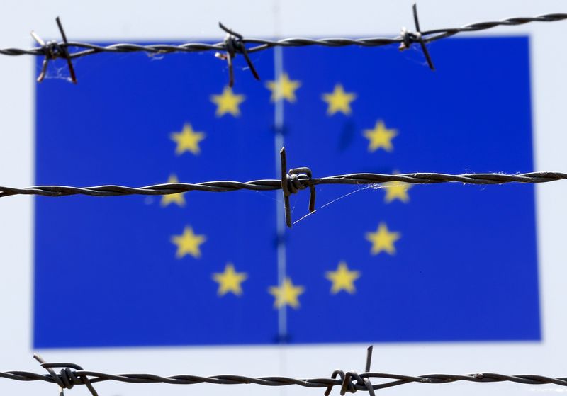© Reuters. A barbed wire is seen in front of a European Union flag at an immigration reception centre in Bicske