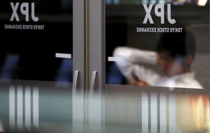 © Reuters. A man looks at a mobile phone at the Tokyo Stock Exchange (TSE) in Tokyo