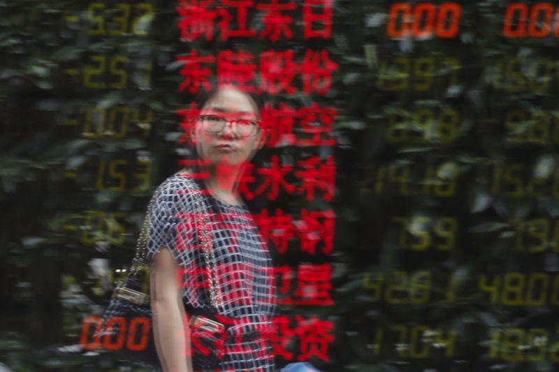 © Reuters. A woman is reflected on an electronic board showing stock information at a brokerage house in Shanghai