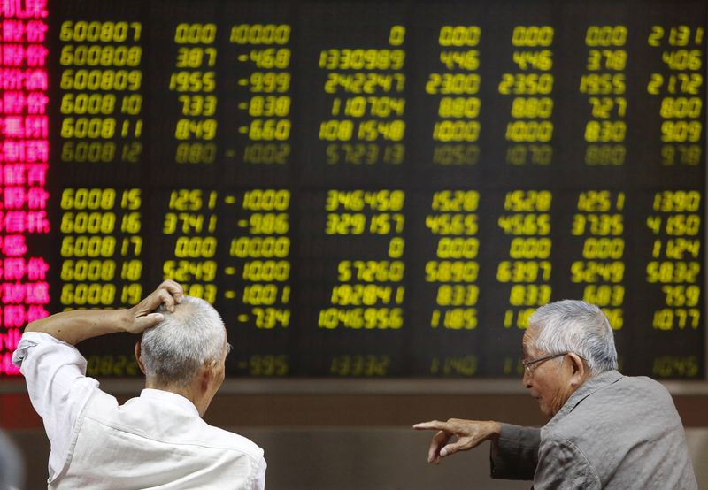 © Reuters. A man watches a board showing stock prices at a brokerage office in Beijing
