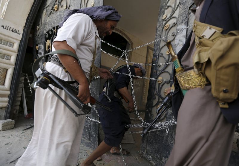 © Reuters. Guards walk through a damaged gate of the house of Brigadier Khaled al-Anduli, an army commander loyal to the Houthi movement, after it was hit by Saudi-led air strikes in Yemen's capital Sanaa