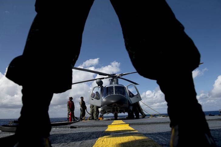 © Reuters. A Philippine Navy personnel stands in front of an Agusta Westland AW109 helicopter before it takes off during CARAT 2014, aboard Philippine Navy vessel BRP Ramon Alcaraz in the South China Sea near waters claimed by China