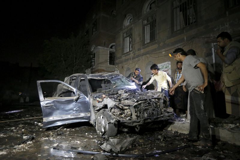 © Reuters. People check a car damaged by a car bomb attack near a mosque in Yemen's capital Sanaa