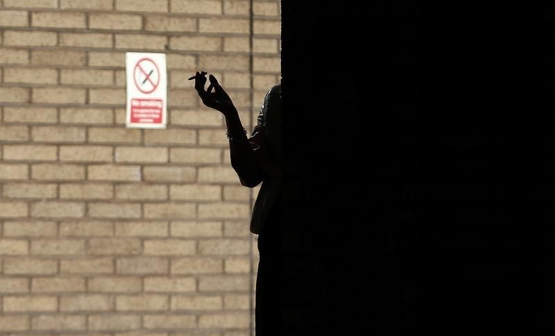 © Reuters. A woman smokes in the shadows outside Southwark Crown Court in central London
