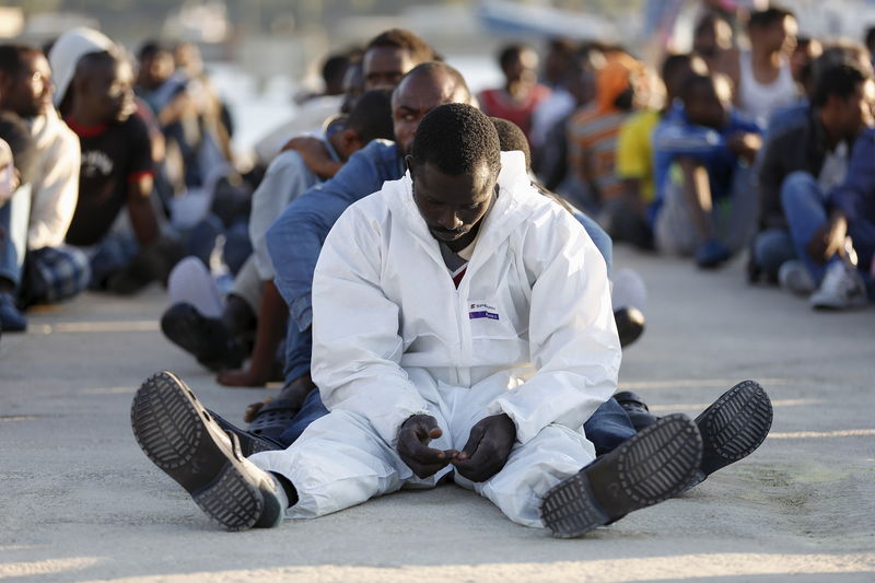 © Reuters. Imigrantes descansam após desembarcarem em porto da Sicília, na Itália