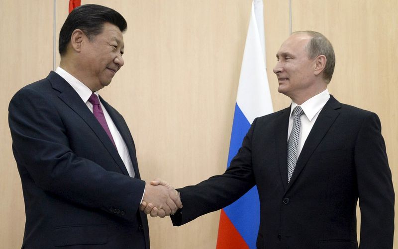 © Reuters. Presidente da Rússia, Vladimir Putin (D), cumprimenta o presidente chinês, Xi Jinping