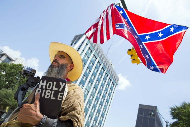 © Reuters. Alan Hoyle of North Carolina holds a confederate battle flag and bible outside the statehouse in Columbia