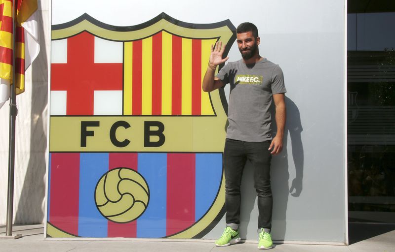 © Reuters. Arda Turan waves in front of the FC Barcelona headquarters before signing his contract in Barcelona