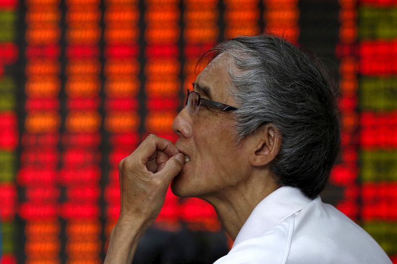 © Reuters. An investor looks at an electronic board showing stock information at a brokerage house in Shanghai 