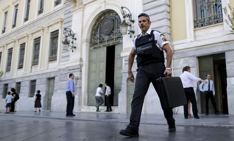 © Reuters. A security worker leaves a National Bank branch after bringing money in central Athens