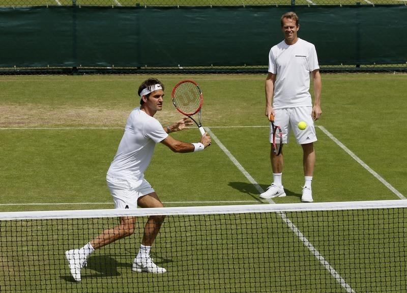 © Reuters. Roger Federer of Switzerland hits a shot as coach Stefan Edberg watches during a practice session at the Wimbledon Tennis Championships in London