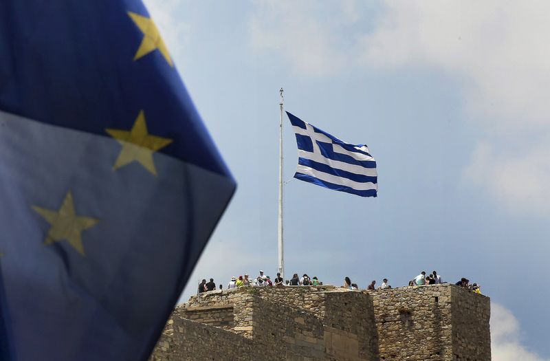 © Reuters. A European Union flag flutters as tourists gather around a Greek flag atop the Acropolis hill in Athens